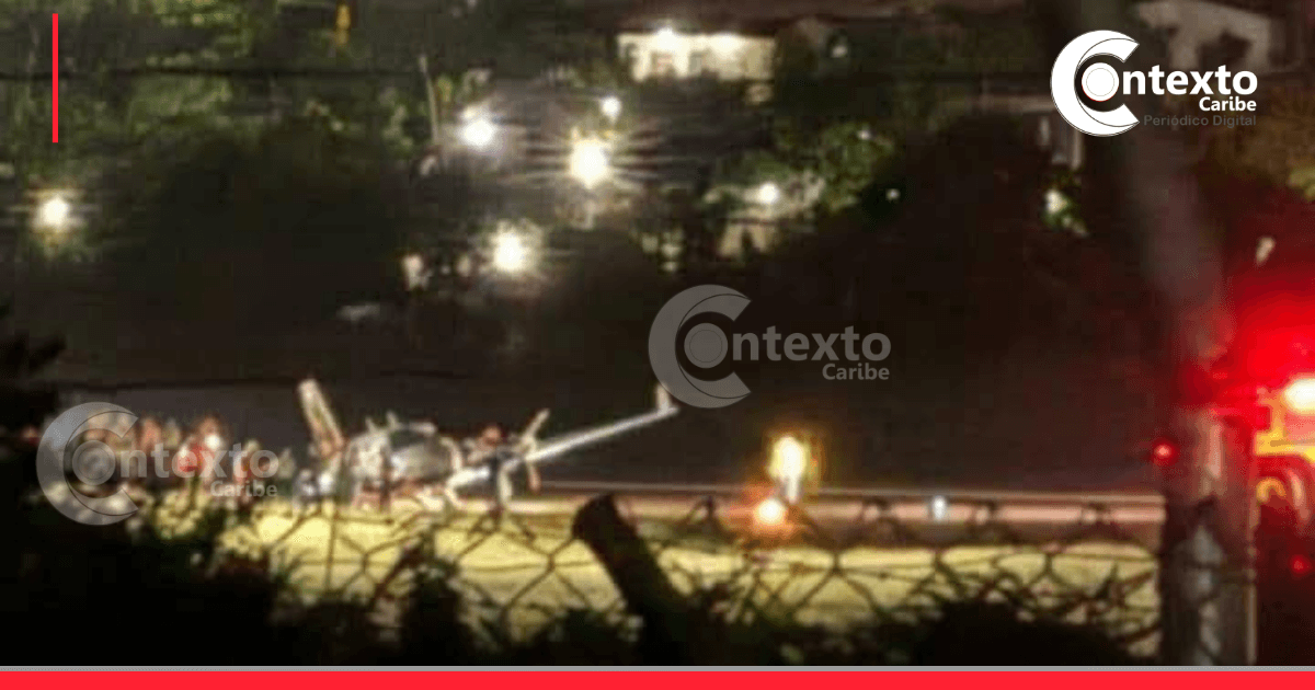 Imagen de un avión accidentado en la noche, con luces de emergencia y equipos de rescate en el lugar.